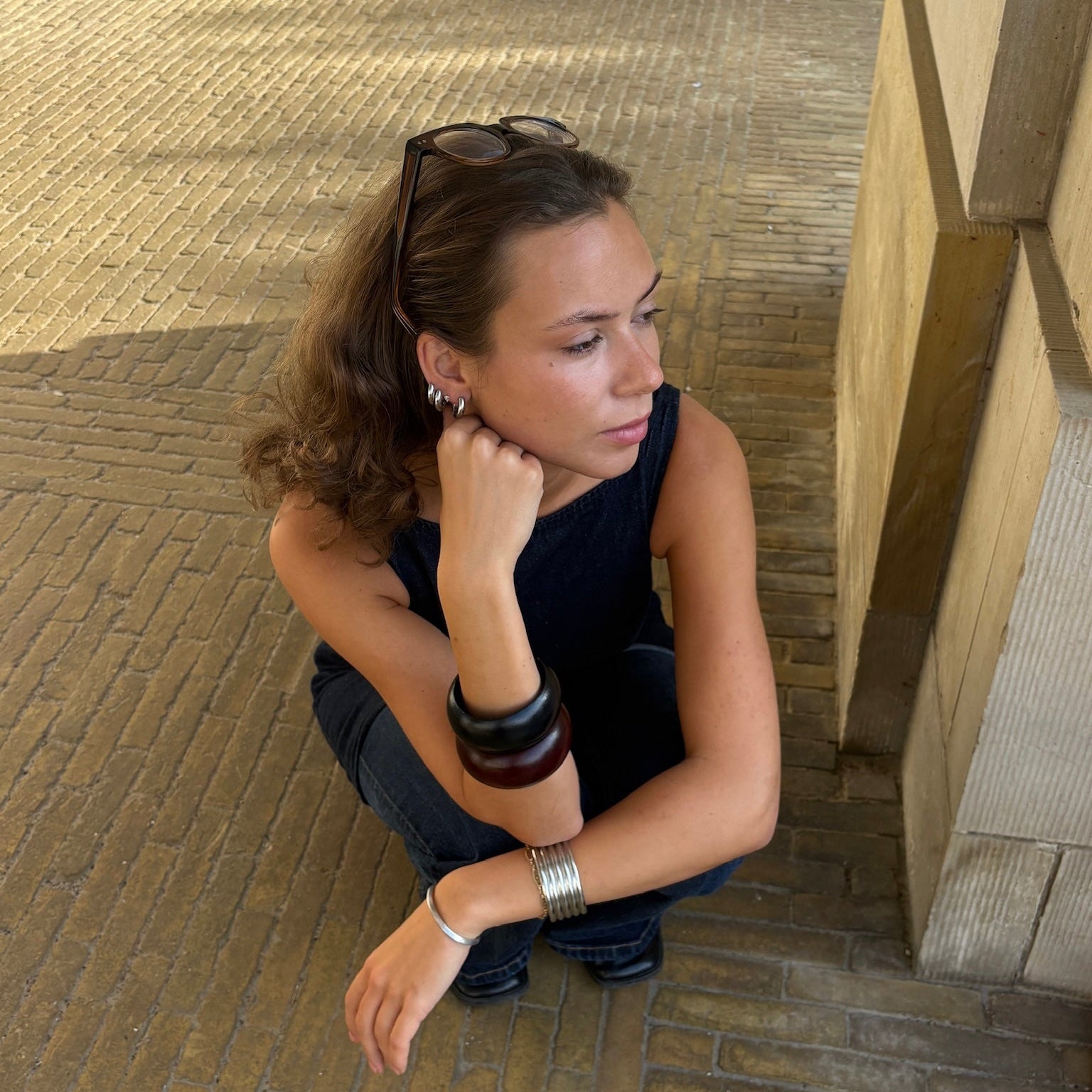Woman sitting on a stone floor with a textured wall in the background